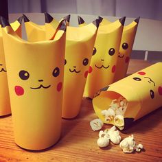 popcorn bags with faces drawn on them sitting on a wooden table next to some snacks