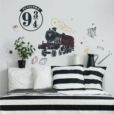 there is a black and white train on the wall above the bed in this bedroom