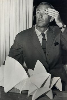 a man in a suit and tie sitting at a table with origami