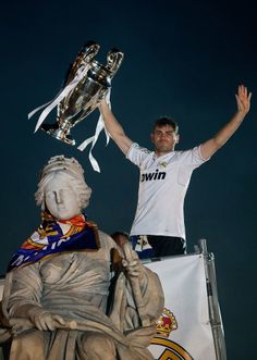 a man standing next to a statue holding up a trophy