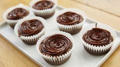 six chocolate cupcakes on a white tray ready to be eaten by someone else