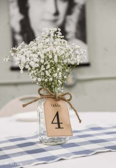 a mason jar filled with baby's breath sitting on top of a blue and white checkered table cloth