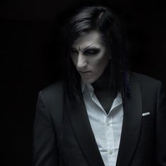 a man in a suit with black hair and makeup