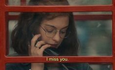 a woman talking on a cell phone with the words i miss you in front of her