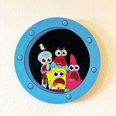 a clock with cartoon characters on it is hanging on the wall in front of a white wall