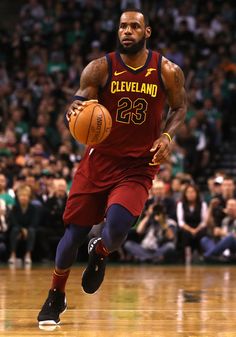 a basketball player dribbling the ball during a game with fans in the stands