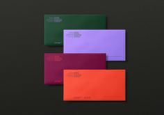 three different colored envelopes on a black surface, one is purple and the other is green