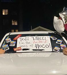 a car with a bunch of balloons on the roof and a sign that says yes wheel be the most ones of hoco