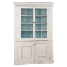 a white china cabinet with glass doors and drawers on the bottom, in front of a white background