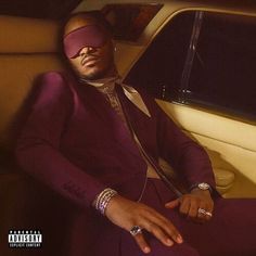 a man in a purple suit and blindfolded head covering sitting in a car