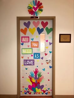 a door decorated with colorful hearts and handprints on it, that says all you need is love