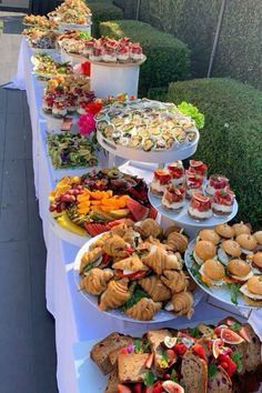 a long table topped with lots of sandwiches and pastries on top of white plates