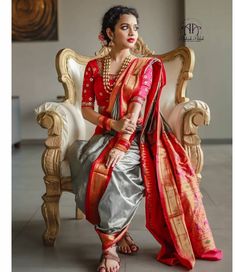 a woman in a red and silver sari sitting on a chair