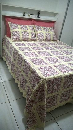 a bed with red and white bedspread sitting on top of a tiled floor