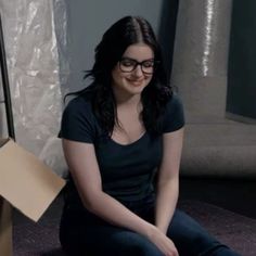 a young woman sitting on the floor in front of a mirror smiling at the camera