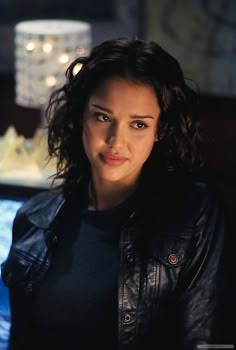 a woman in black jacket sitting next to a cake