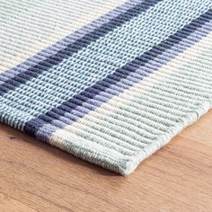 a close up of a rug on a wooden floor with blue and white stripes in the middle