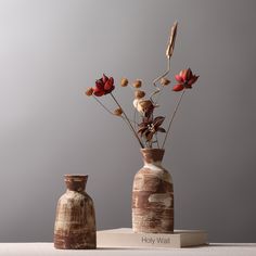 two vases with flowers in them sitting on a table