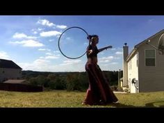 a woman in a long dress is holding a hula hoop and looking at the sky