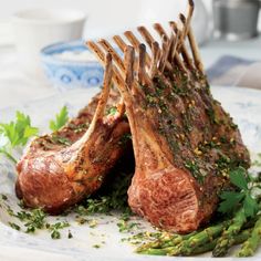 two raw lamb chops on a plate with asparagus and parsley garnish