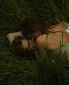 a man and woman are laying in the grass