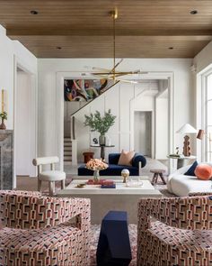 a living room filled with lots of furniture next to a stair case on the wall