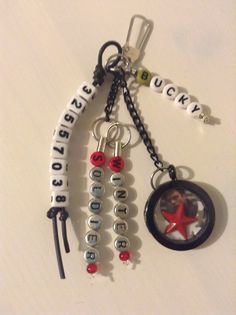 two key chains with charms attached to them on a white surface, one has a red star and the other is a black circle