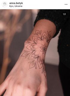 a woman's hand with a flower tattoo on the middle of her left wrist