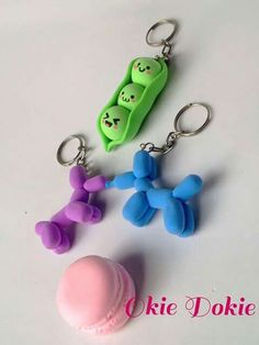 three key chains with two peas, one pink and one green on them sitting next to each other