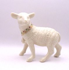 a white sheep figurine with a colorful beaded collar on it's neck