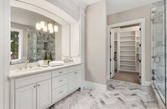 a large bathroom with marble flooring and white cabinets, along with a walk - in shower