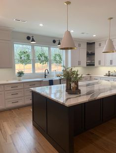 a large kitchen with an island in the middle and two pendant lights hanging from the ceiling