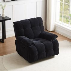 a black recliner sitting on top of a rug in front of a white wall