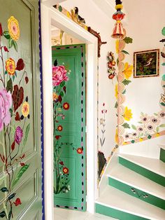 a green door with flowers painted on it and some stairs leading up to the second floor