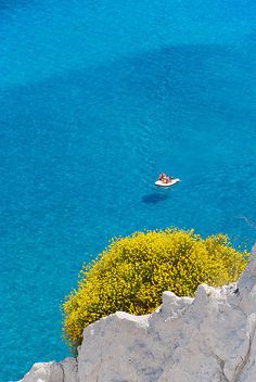 a boat is in the blue water near some rocks