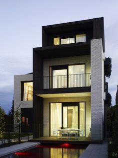 a house with a pool in front of it and two balconies on the second floor