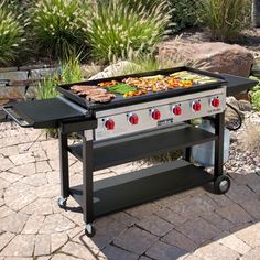 an outdoor grill with various foods cooking on it