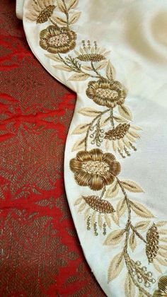 an embroidered table cloth with gold flowers and leaves on red velvet background, closeup