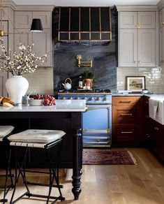 a kitchen with an island and stools in front of the counter top, along with two vases filled with flowers