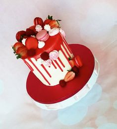 a red and white cake with strawberries on top is sitting on a heart shaped plate