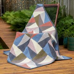 a blanket sitting on top of a wooden floor next to a chair and potted plant