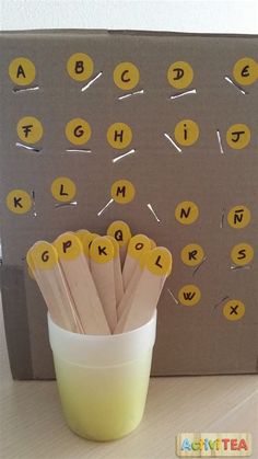 a cup filled with yellow paper straws sitting next to a cardboard board and letters