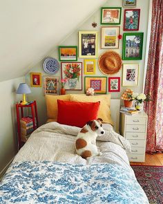 a dog laying on top of a bed in a room with many framed pictures above it