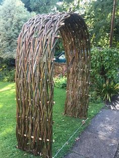 an outdoor sculpture made out of branches in the grass