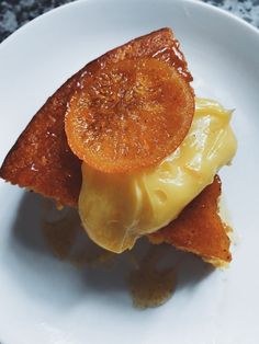 a white plate topped with two pieces of bread covered in cheese and an orange slice