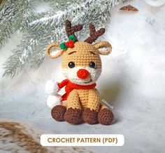 a crocheted reindeer sitting in front of a christmas tree