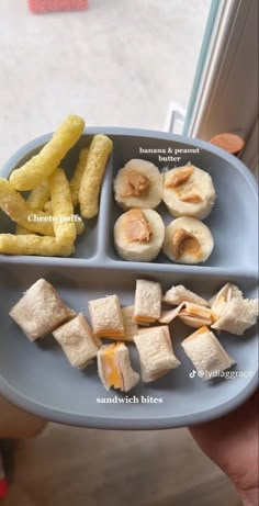 a person holding a blue plate with food on it that includes crackers and bananas