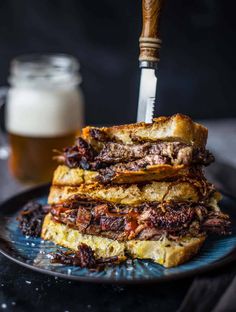 a stack of french toast sitting on top of a blue plate next to a glass of beer