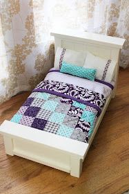 a small bed with a purple and blue quilt on it