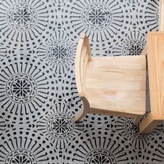 a wooden chair sitting on top of a black and white floor next to a wall